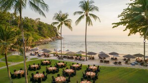 A beachfront restaurant with outdoor seating, palm trees, and ocean views. - Phuket Marriott Resort & Spa, Merlin Beach (Patong)