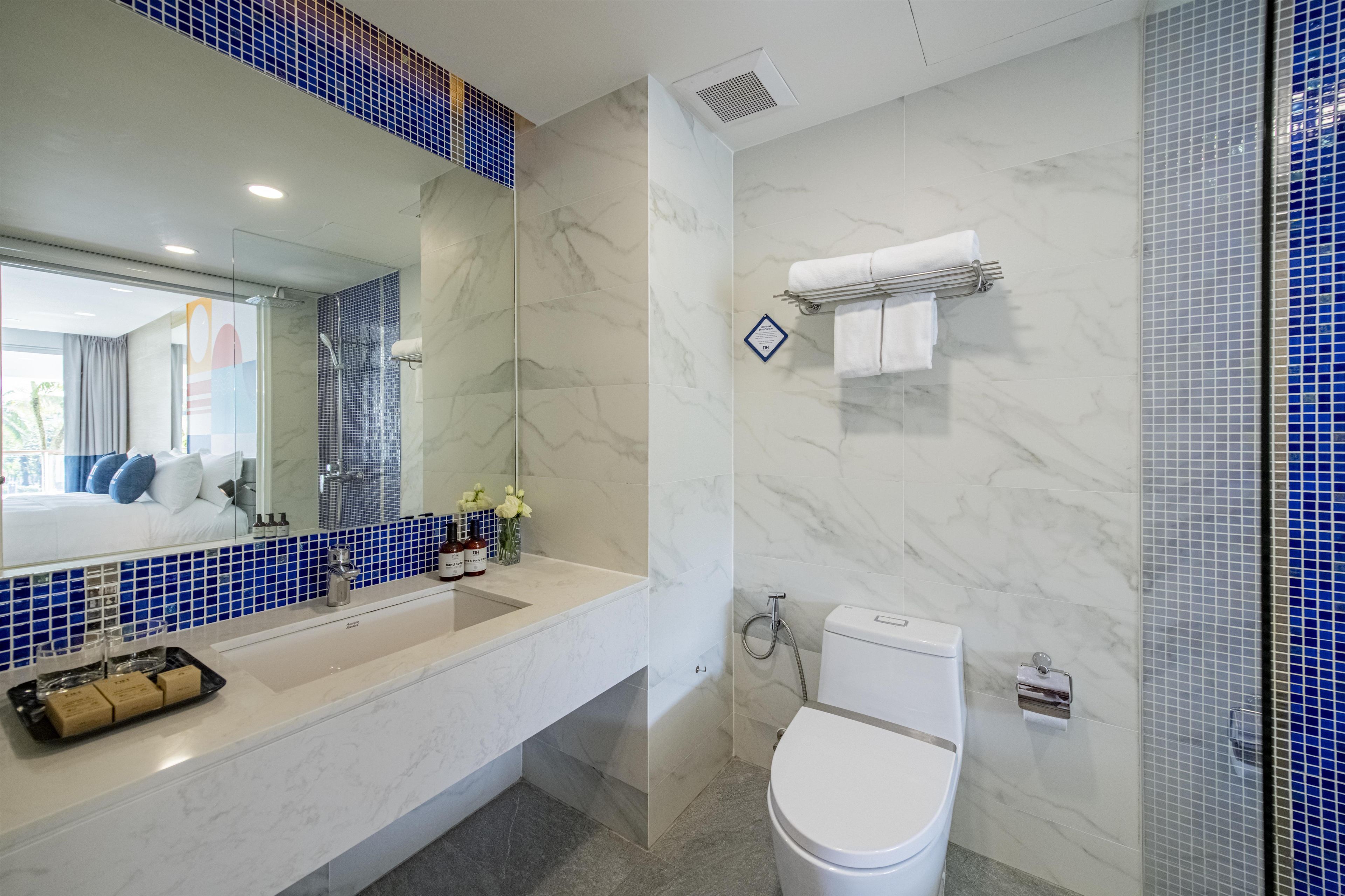 Un baño con inodoro blanco, lavabo con espejo y zona de ducha.