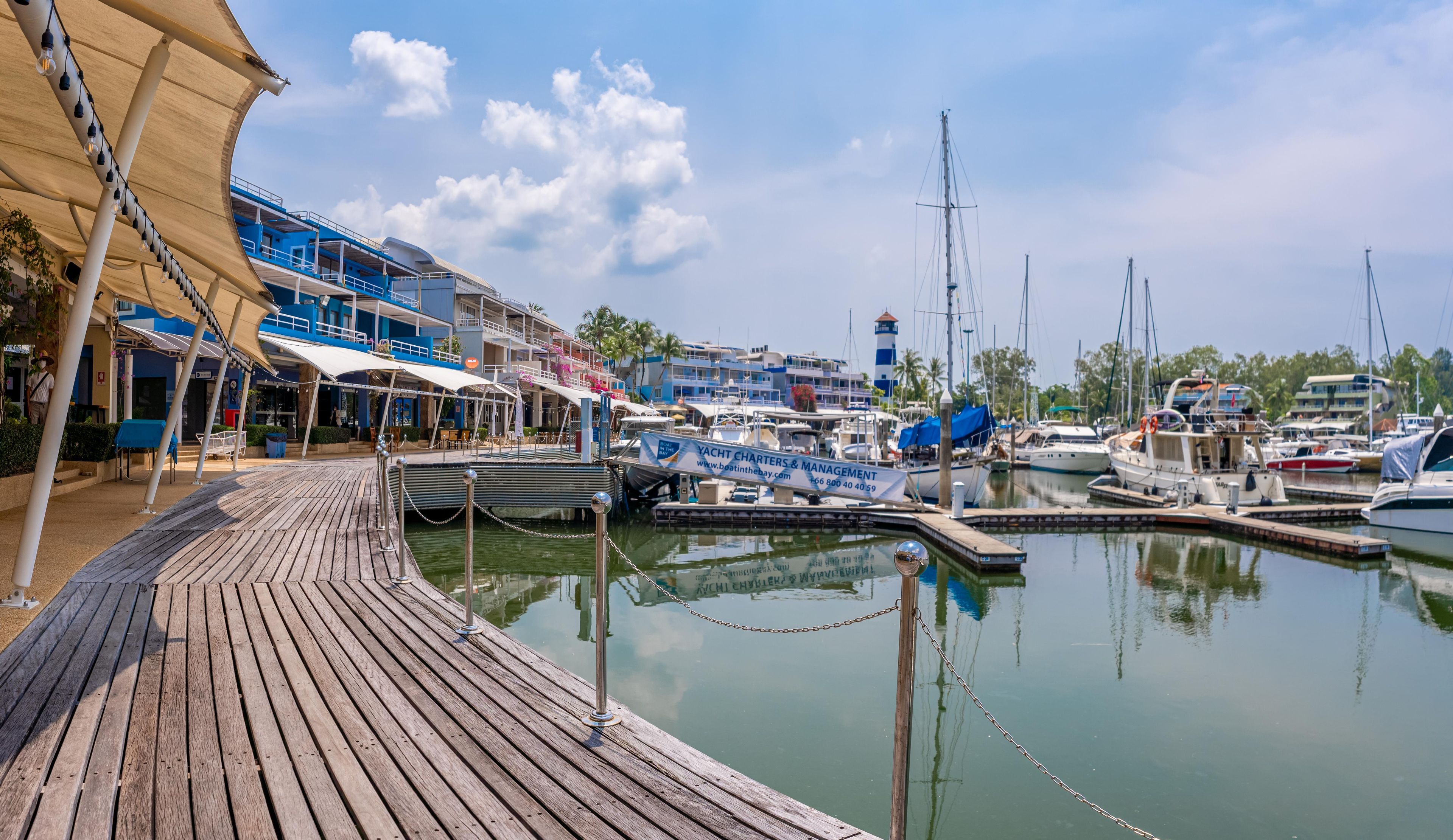 A marina with docked boats, a wooden pier, and a building with a blue facade.