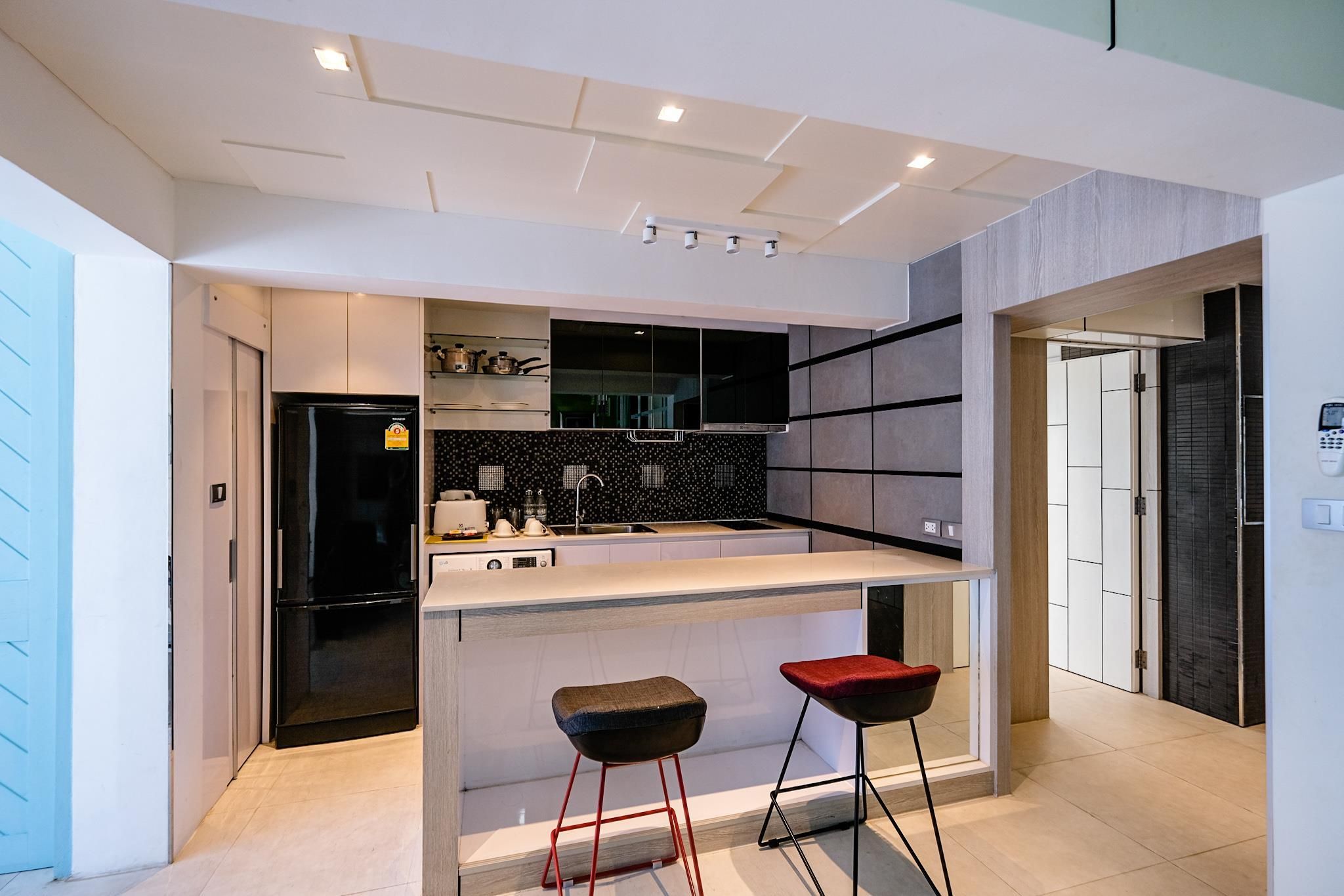 A modern kitchen with a central island, bar stools, and a built-in oven.