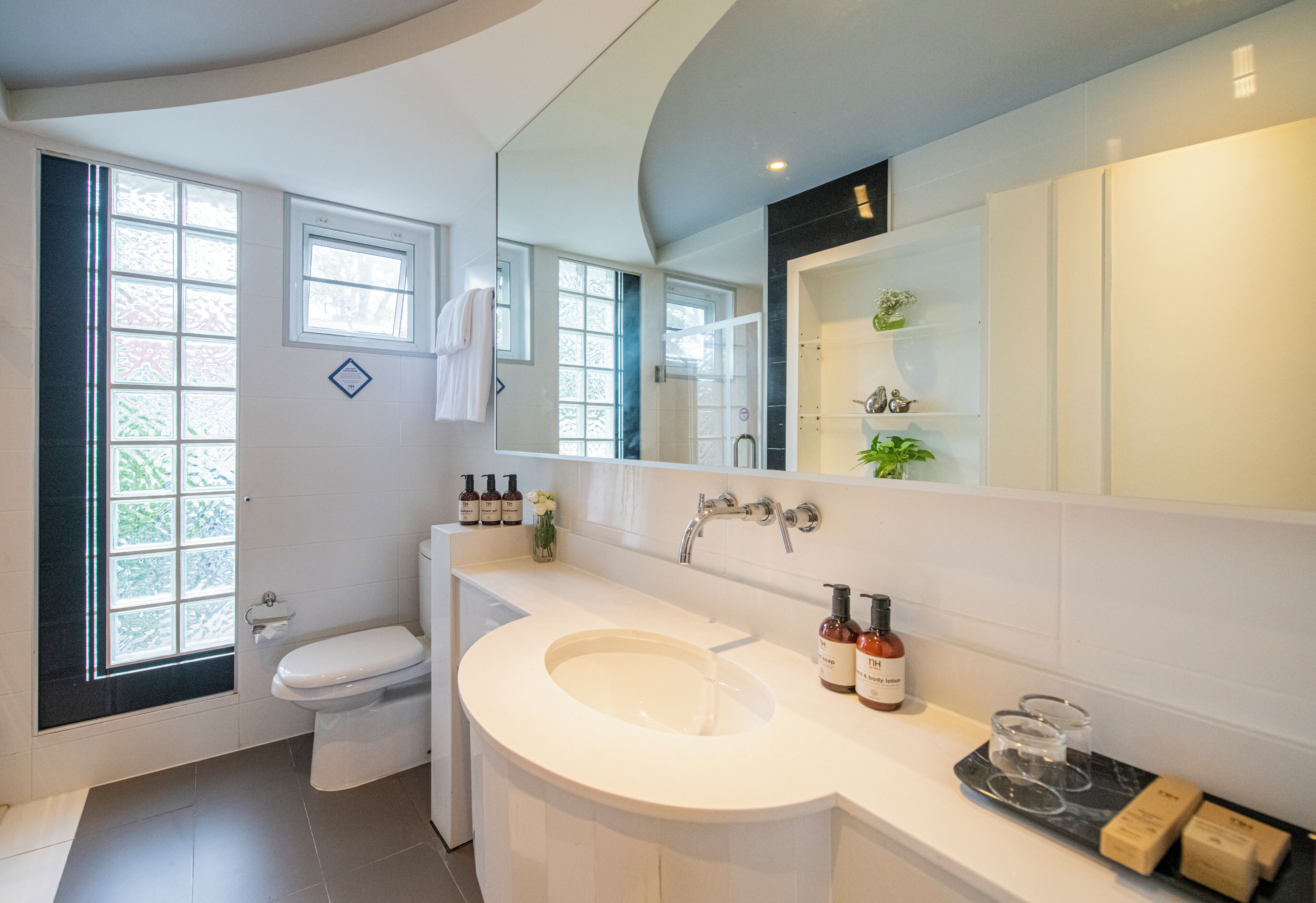 Een moderne badkamer met een groot wastafel, toilet en een raam.