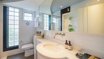 A modern bathroom with a large sink, toilet, and a window.
