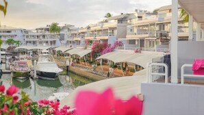 A marina with boats docked, a covered walkway, and buildings with balconies. - NH Boat Lagoon Phuket Resort (Ko Kaeo)