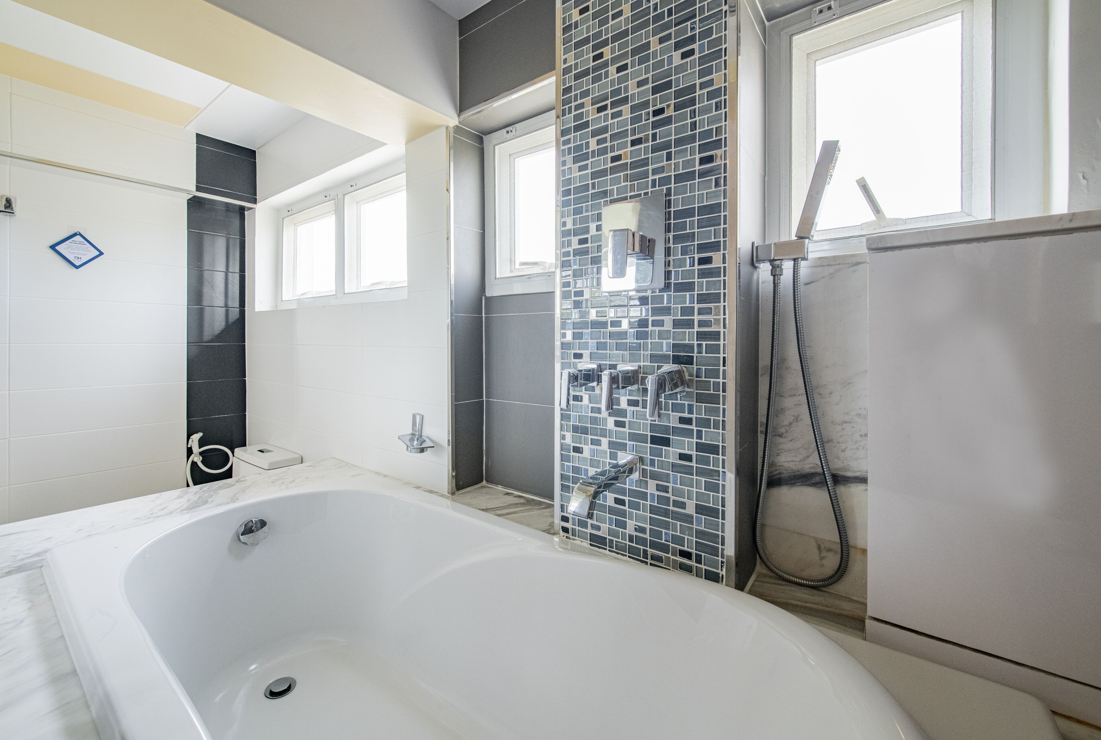 A modern bathroom with a large bathtub, a shower area with a glass wall, and a window providing natural light.