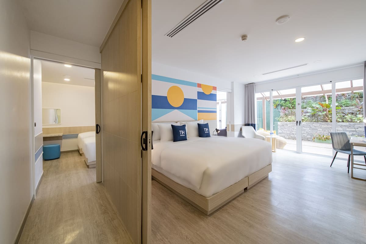 Quarto de hotel moderno com uma cama grande, uma escrivaninha e vista para o jardim.