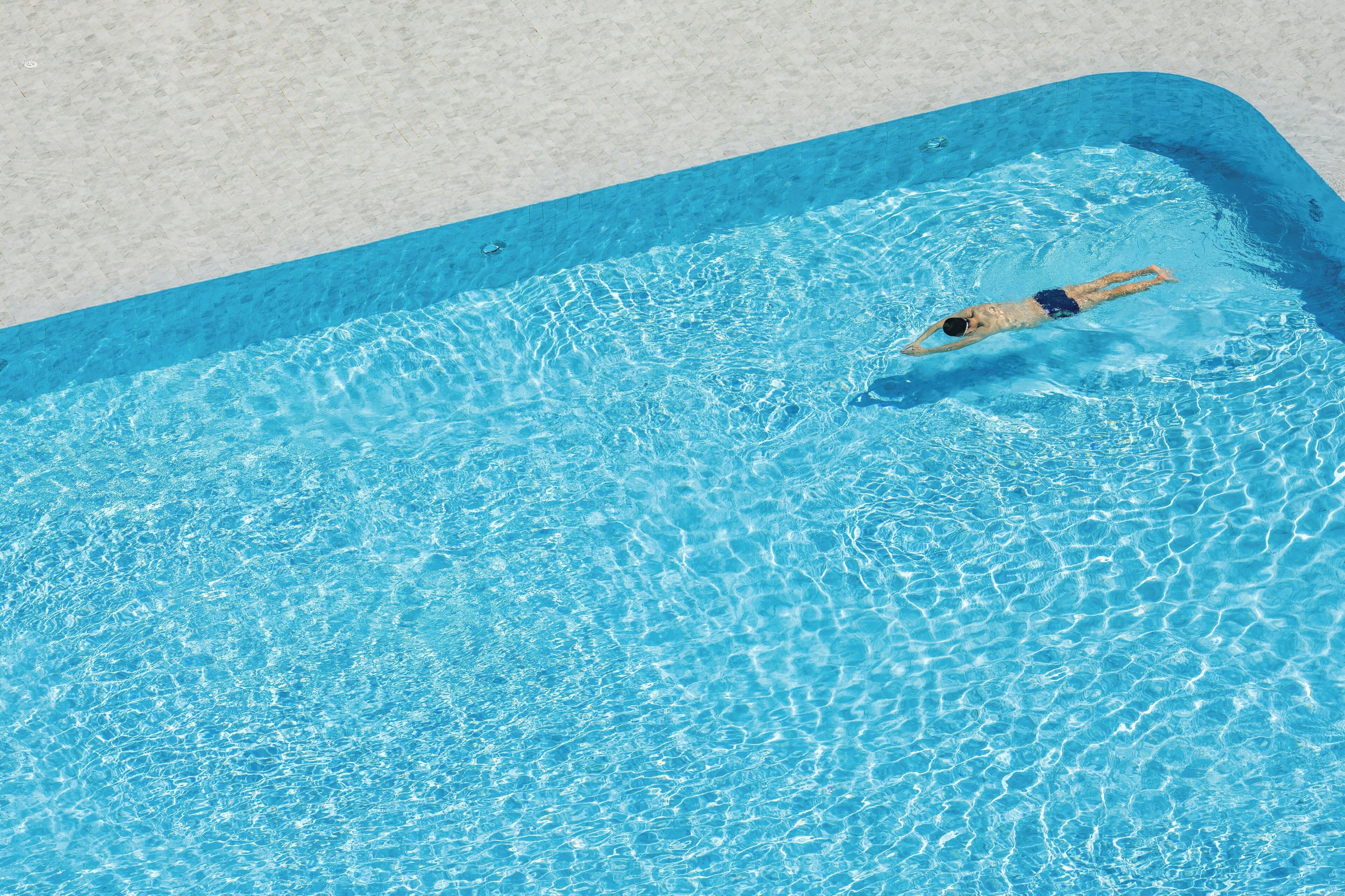 Ein Schwimmbad mit klarem, blauem Wasser und einer darin schwimmenden Person.