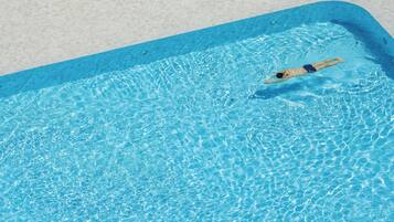 Ein Schwimmbad mit klarem, blauem Wasser und einer darin schwimmenden Person.