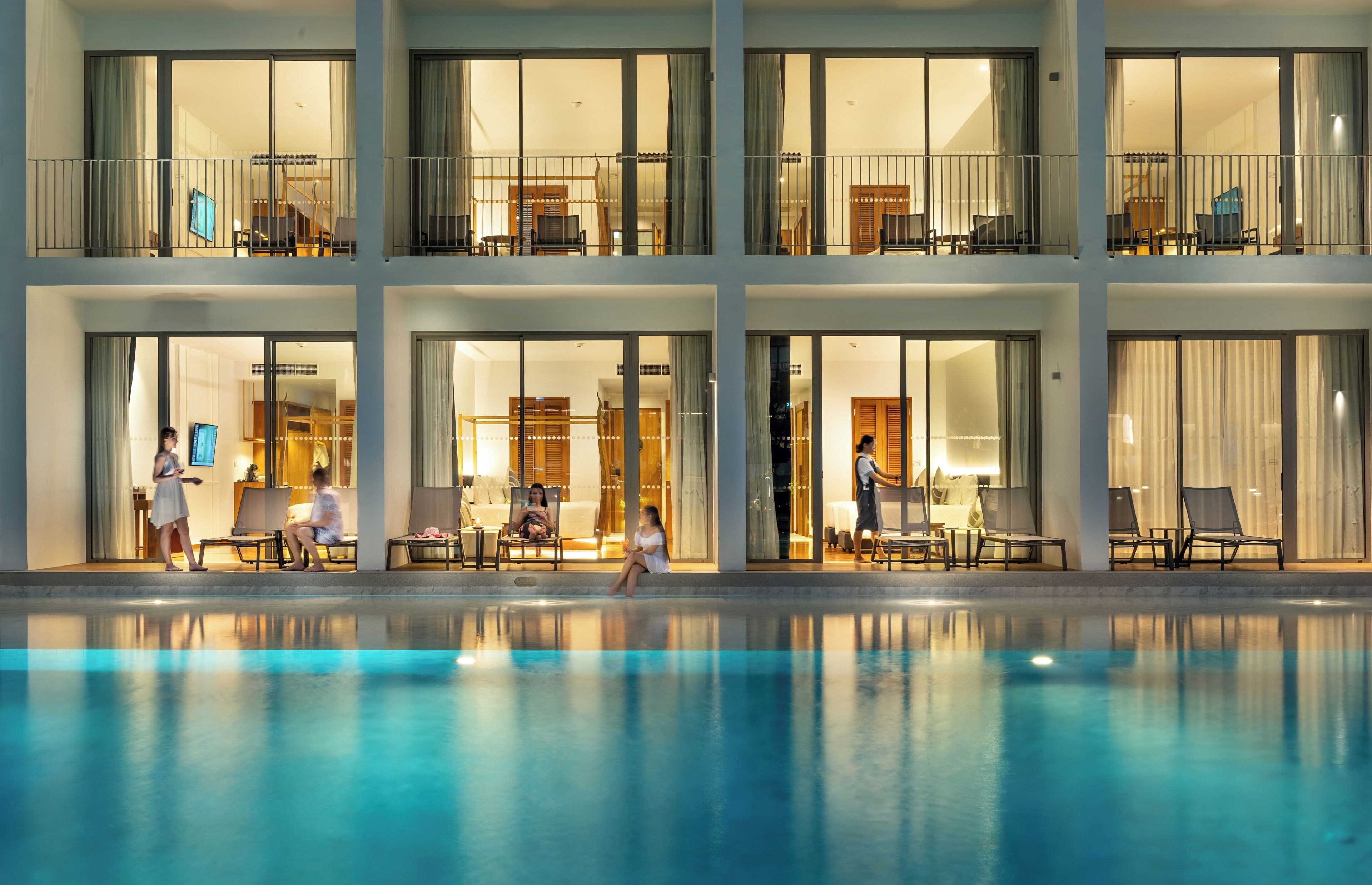 A multi-story hotel with balconies, a swimming pool, and indoor seating areas.