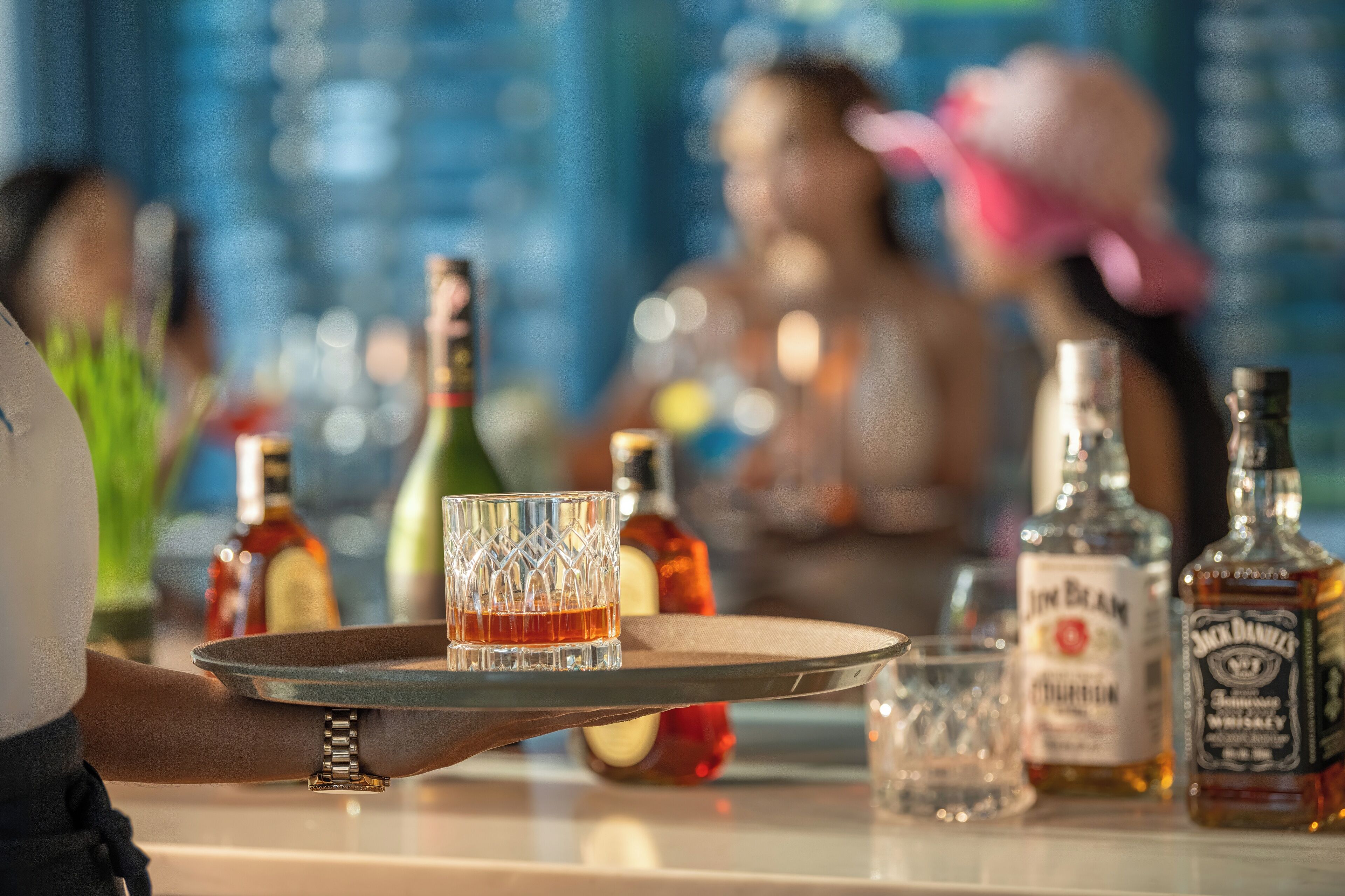 A bar setting with a tray of drinks, bottles, and glasses.