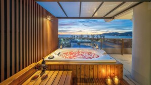 A wooden deck with a hot tub, wine glasses, and candles. - Patong Beach Hotel by See2Sea (Patong)