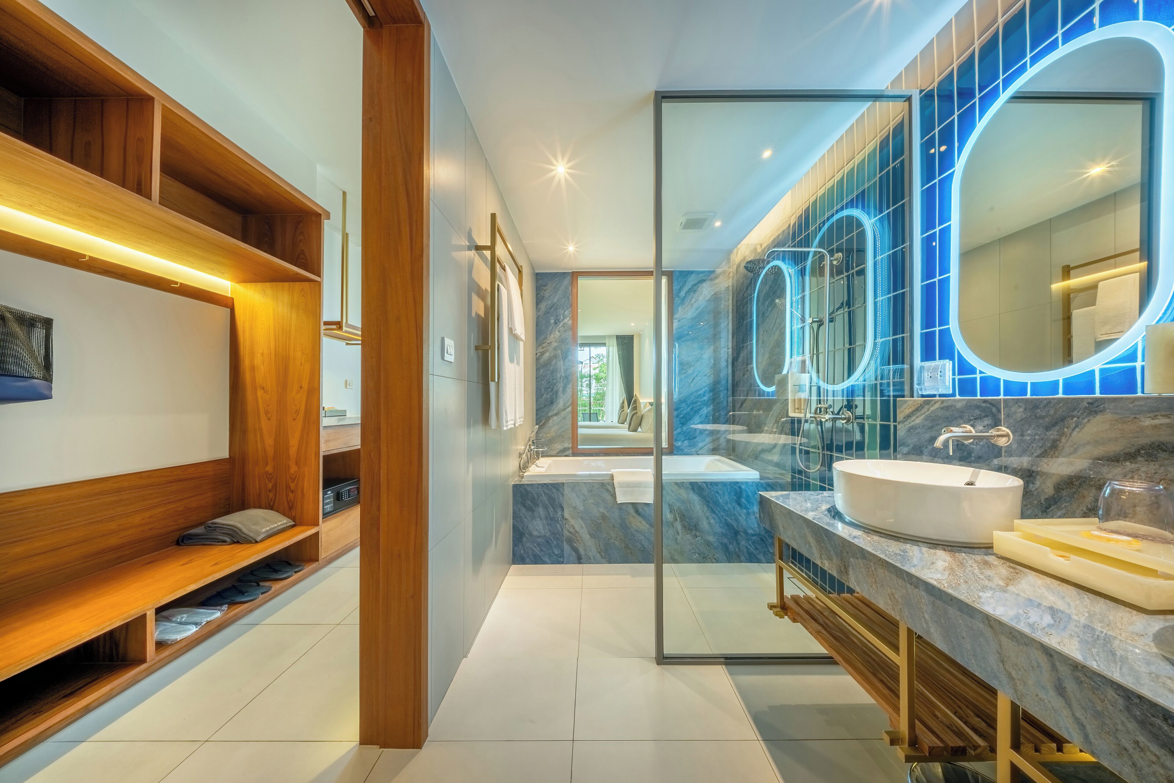 A modern bathroom with a glass-enclosed shower, a vanity with a large mirror, and a wooden shelving unit.