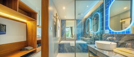 A modern bathroom with a glass-enclosed shower, a vanity with a large mirror, and a wooden shelving unit.