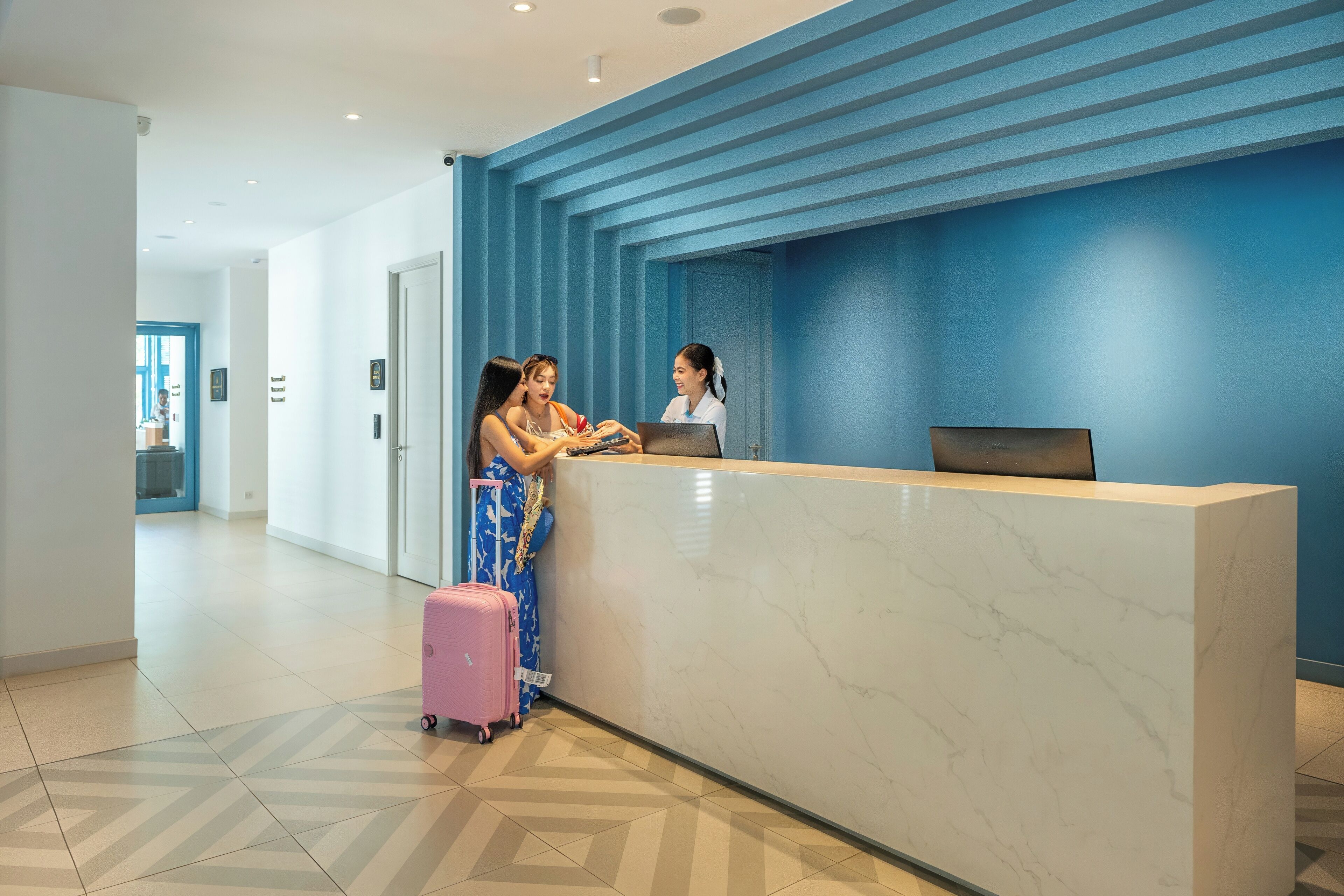 A hotel reception area with a marble counter, a blue wall, and a tiled floor.
