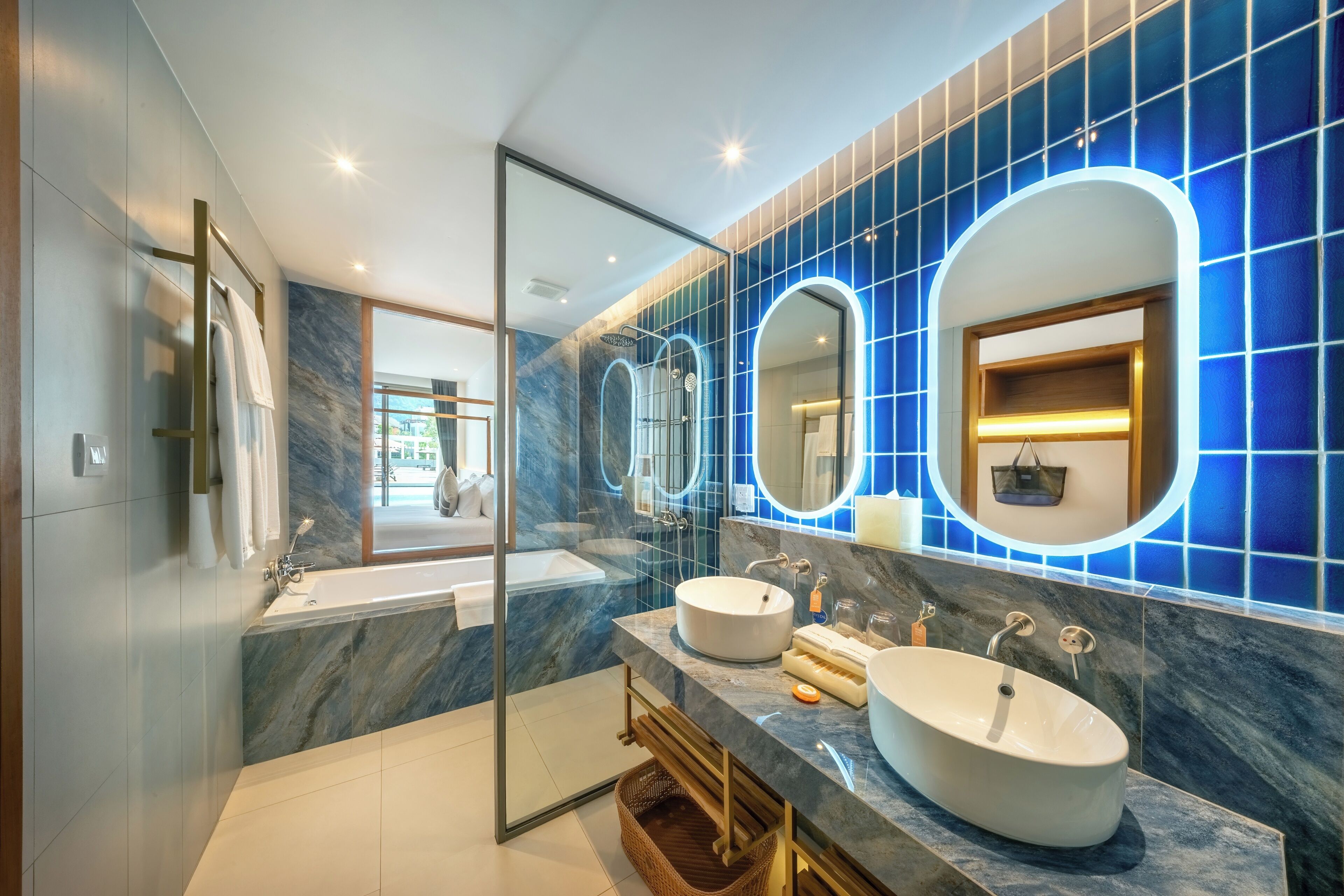 Un baño moderno con dos lavamanos, cabina de ducha de vidrio y salpicadero de mármol.