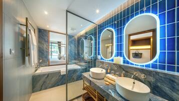 Un baño moderno con dos lavamanos, cabina de ducha de vidrio y salpicadero de mármol.