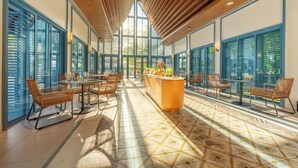 A spacious indoor area with large windows, a central bar, and seating arrangements. - Patong Beach Hotel by See2Sea (Patong)