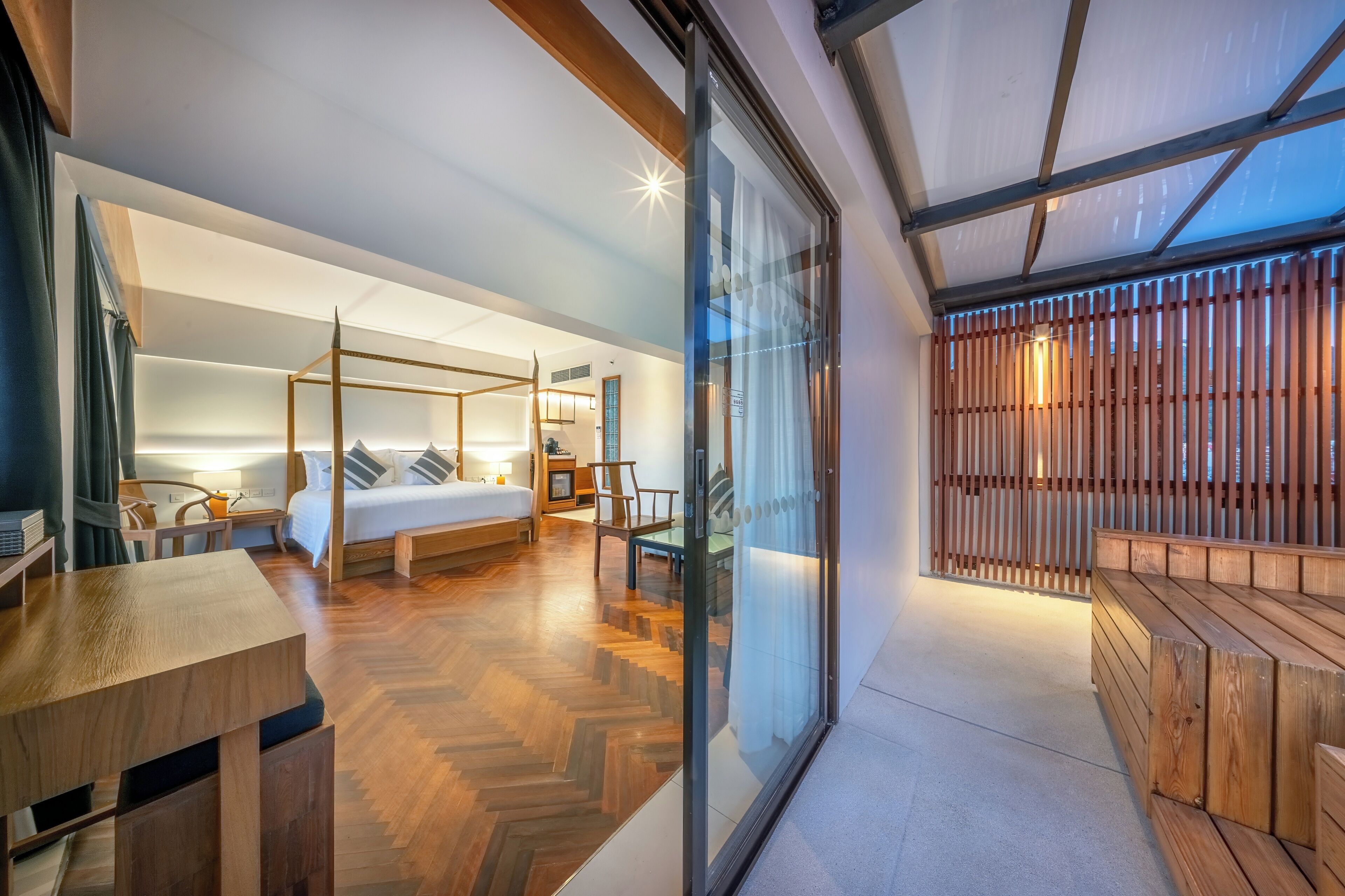 A modern bedroom with a four-poster bed, a wooden desk, and a glass partition.