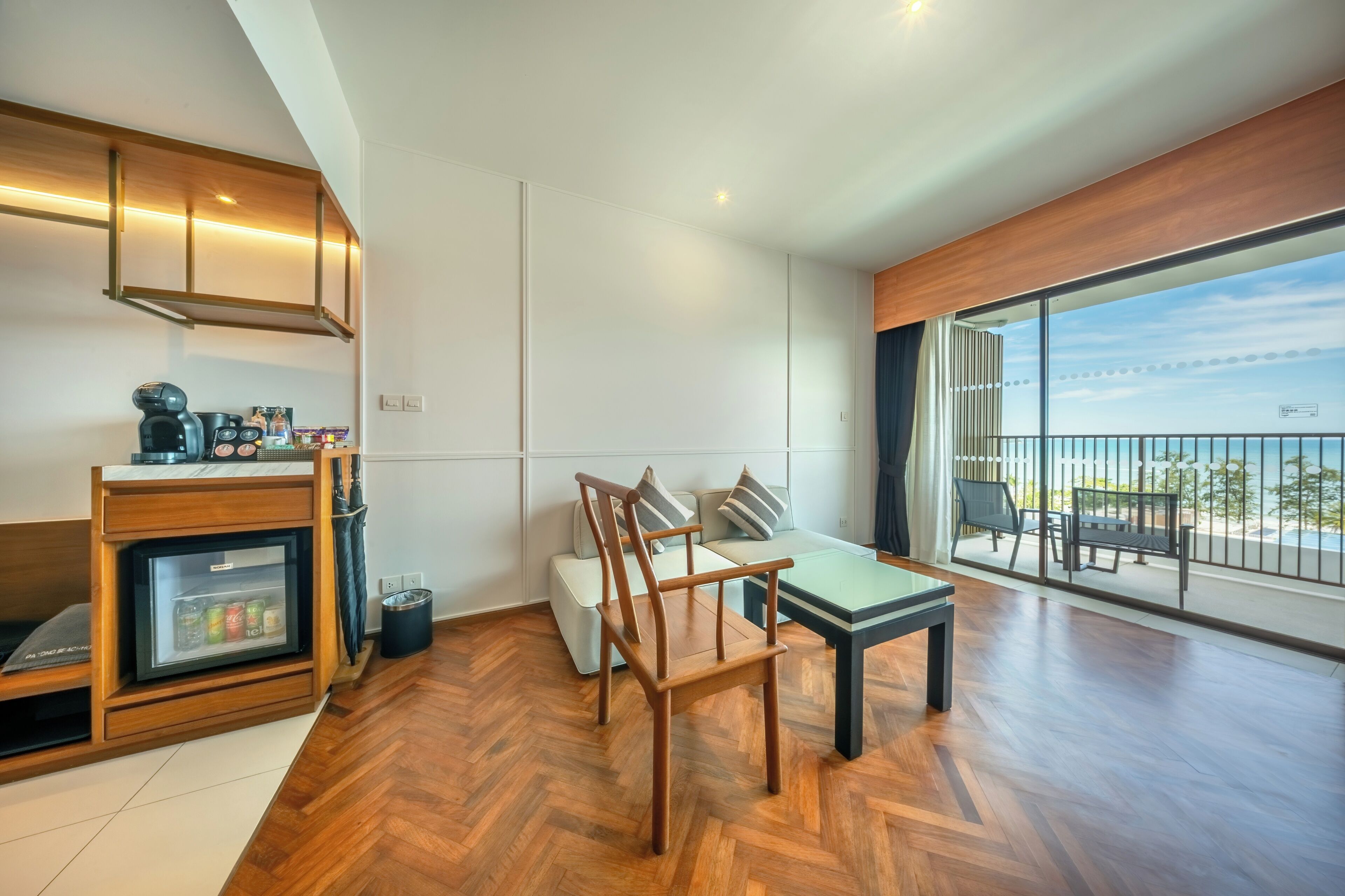 A modern kitchen with a built-in refrigerator, a dining area with a table and chairs, and a balcony with a view of the sea.