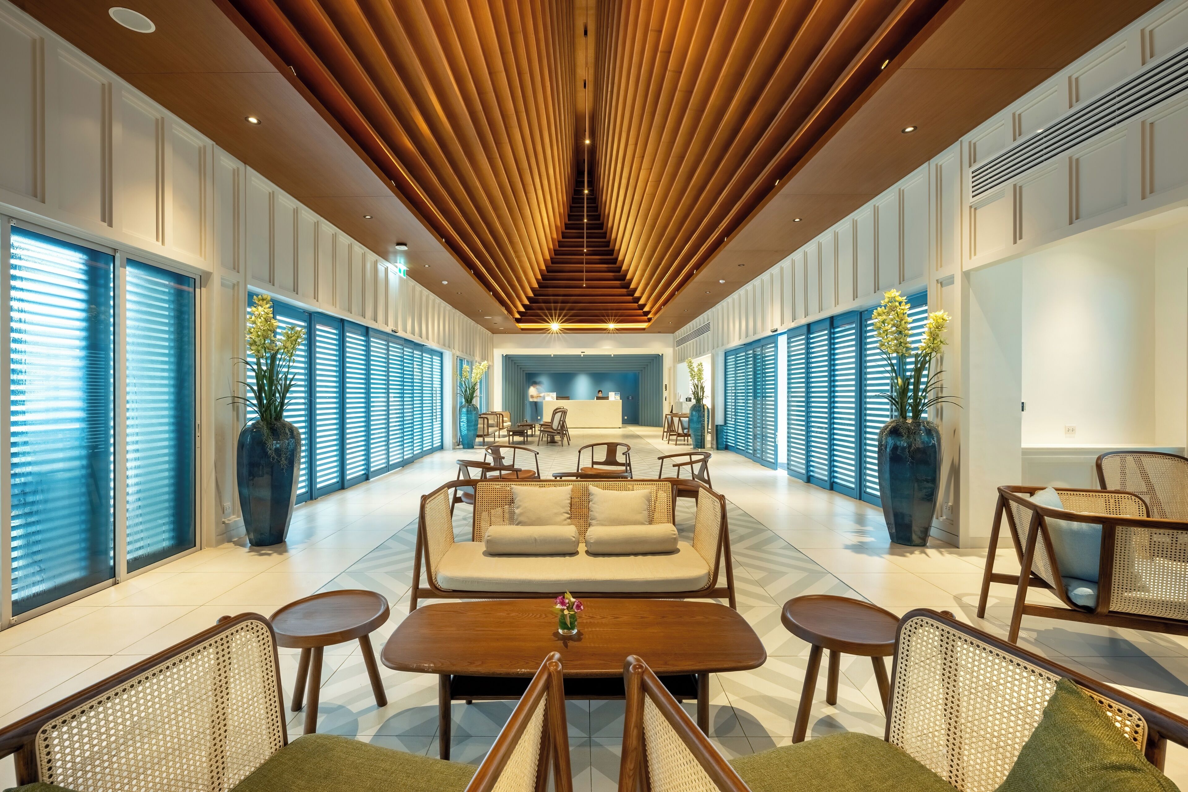 A spacious lobby with a central seating area, large windows, and a modern ceiling design.