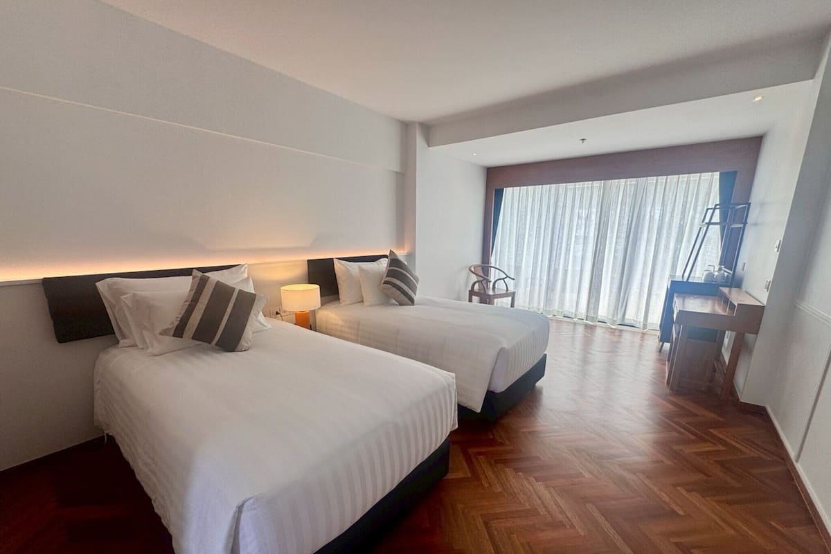 A hotel room with two beds, a desk, and a chair.