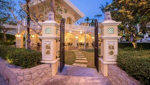 A well-lit entrance with a stone pathway leading to a covered patio area. - The Front Village (Karon)