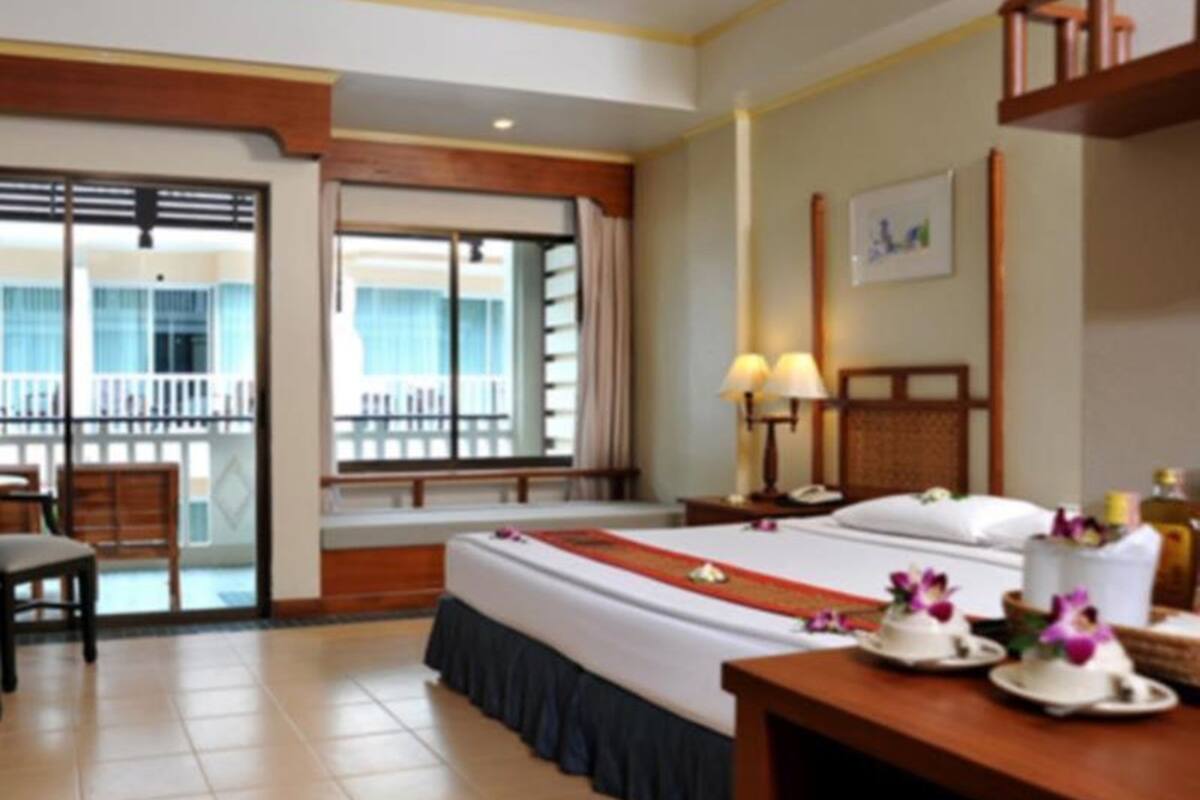 A hotel room with a bed, a desk, a chair, a window with a view, and a balcony.
