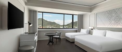 A hotel room with a large window, a bed, a desk, and a chair.