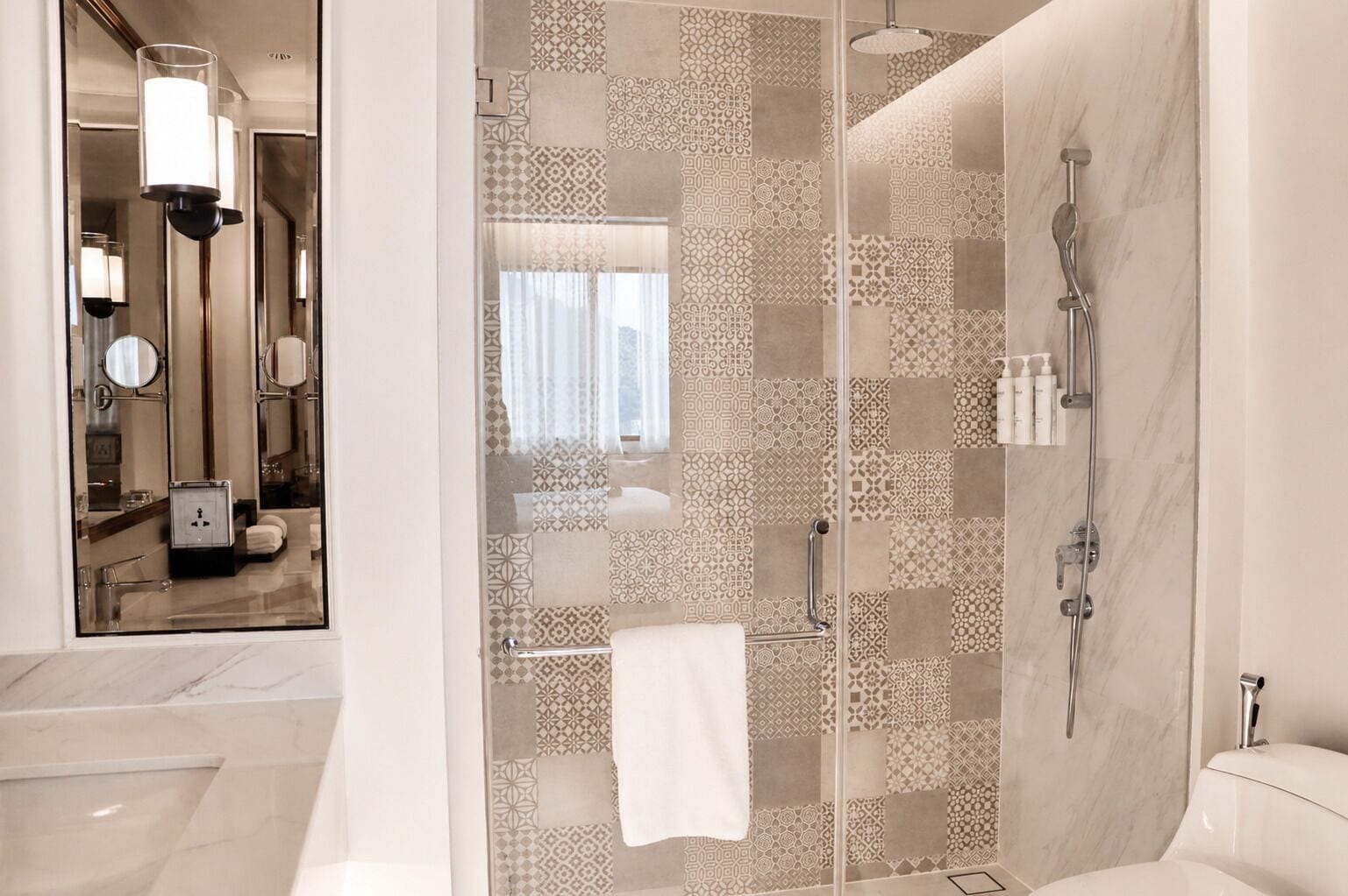 Un baño moderno con cabina de ducha de vidrio, inodoro blanco y lavamanos con toallero.