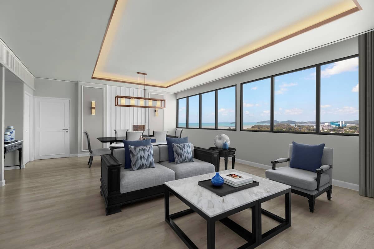 Un salon moderne avec un canapé, des fauteuils et une table basse. De grandes fenêtres offrent une vue sur la ville.