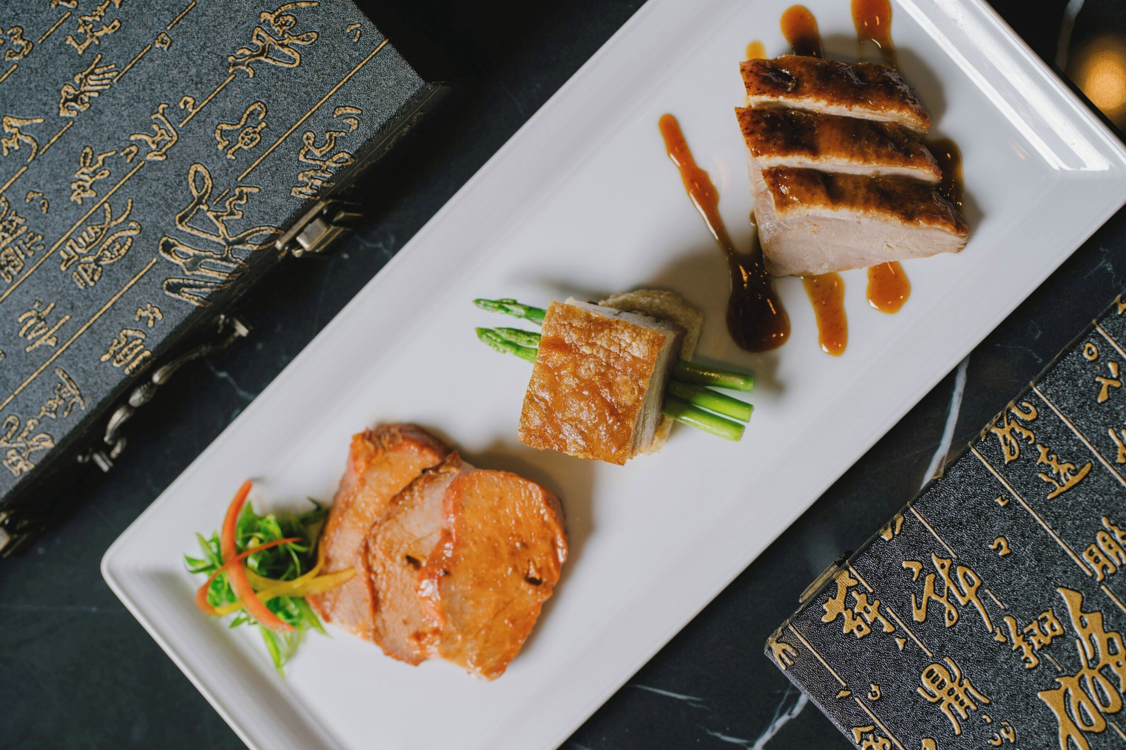 A white rectangular plate with food items and a decorative book with gold script.