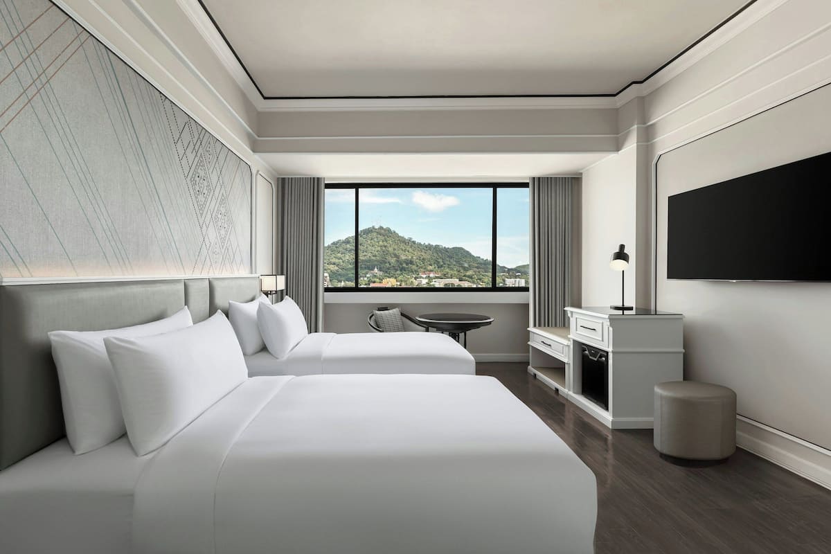 Une chambre d’hôtel moderne équipée de deux lits, d’un bureau, d’une chaise et d’un téléviseur.