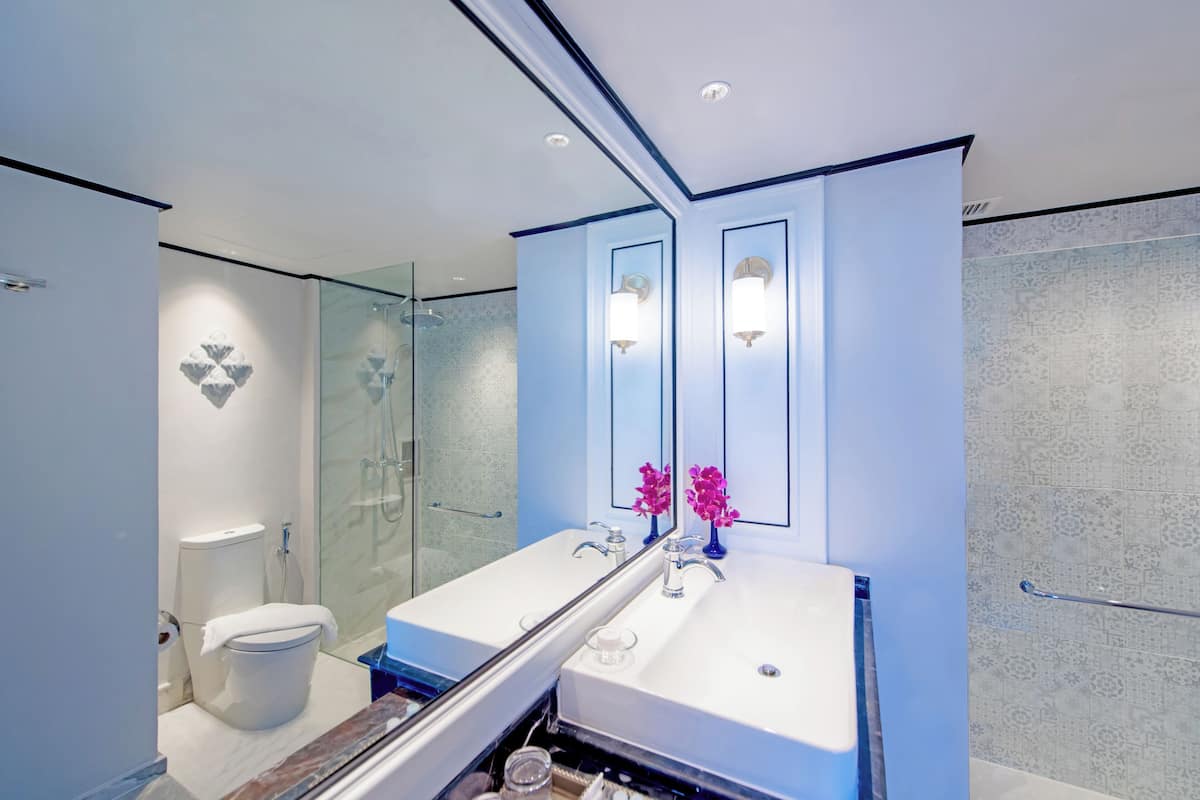 Ein modernes Badezimmer mit Duschkabine aus Glas, einem Waschbecken mit Spiegel und einer Toilette.
