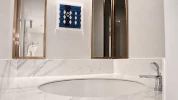 A bathroom with a large oval sink, a mirror, and a towel rack with a patterned towel.