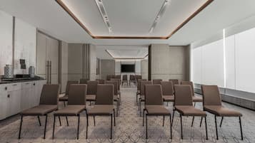 A conference room with rows of chairs, a long table, and a patterned carpet.