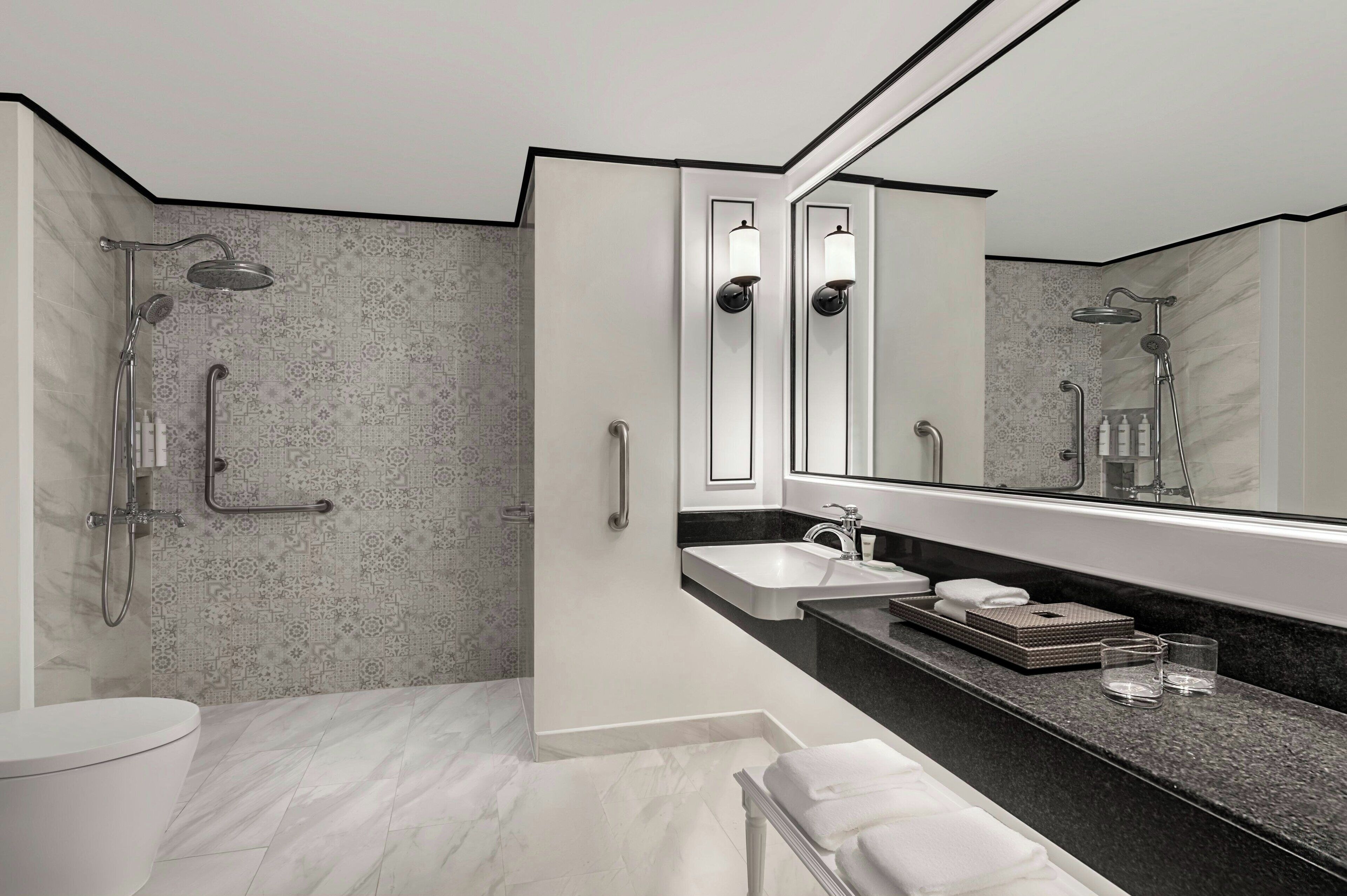 Un baño moderno con cabina de ducha, un espejo grande y tocador con lavabo y encimera.