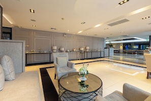 A modern lobby with a reception desk, seating area, and a decorative plant. - Pearl Hotel Phuket (Phuket)