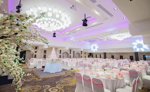 A banquet hall with round tables, a stage, and a floral arch. - Pearl Hotel Phuket (Phuket)