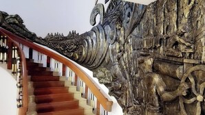 A staircase with a wooden handrail and a wall with a dragon relief sculpture. - Pearl Hotel Phuket (Phuket)