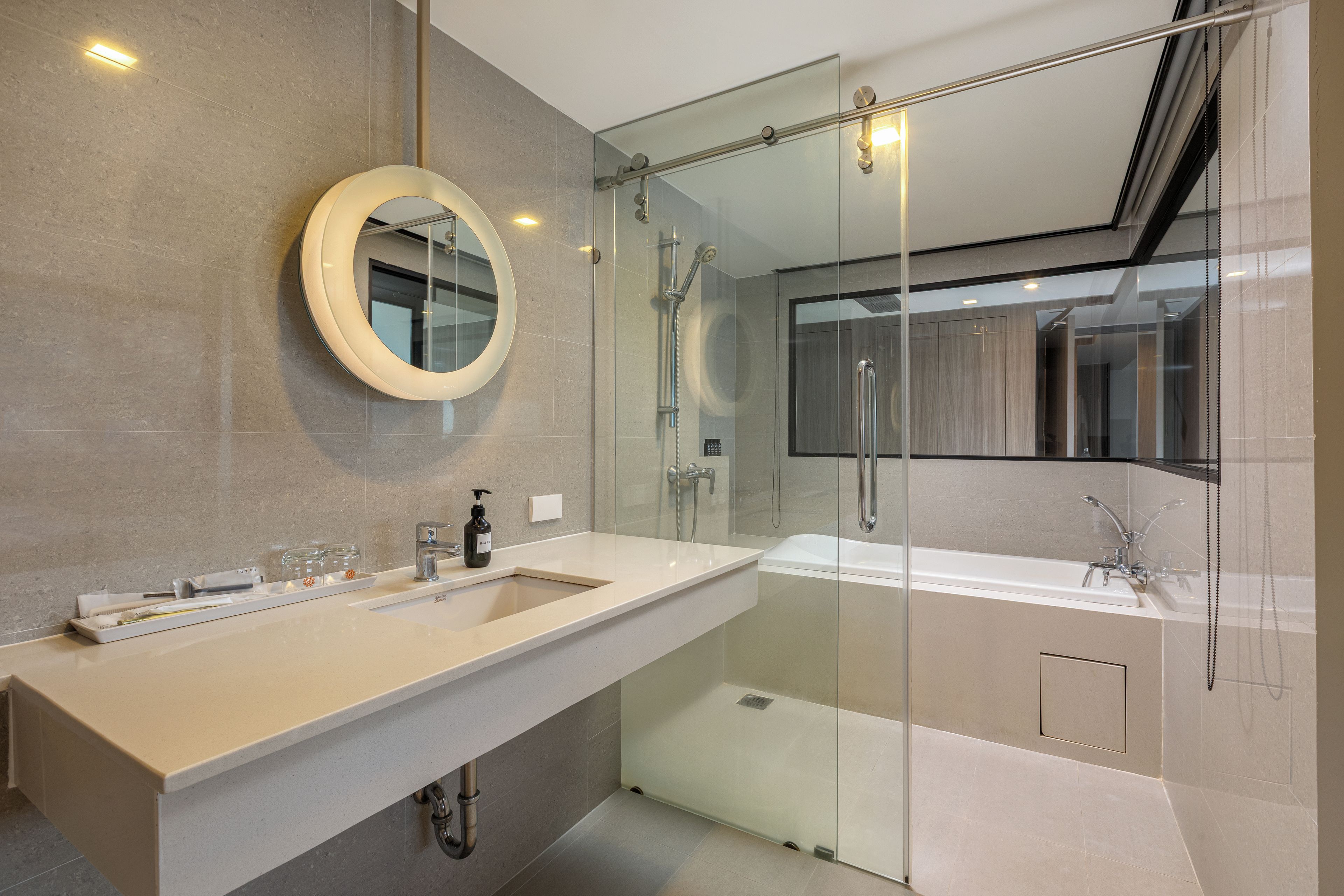 Un baño moderno con ducha envuelta en vidrio, un espejo grande y un mueble de tocador doble.