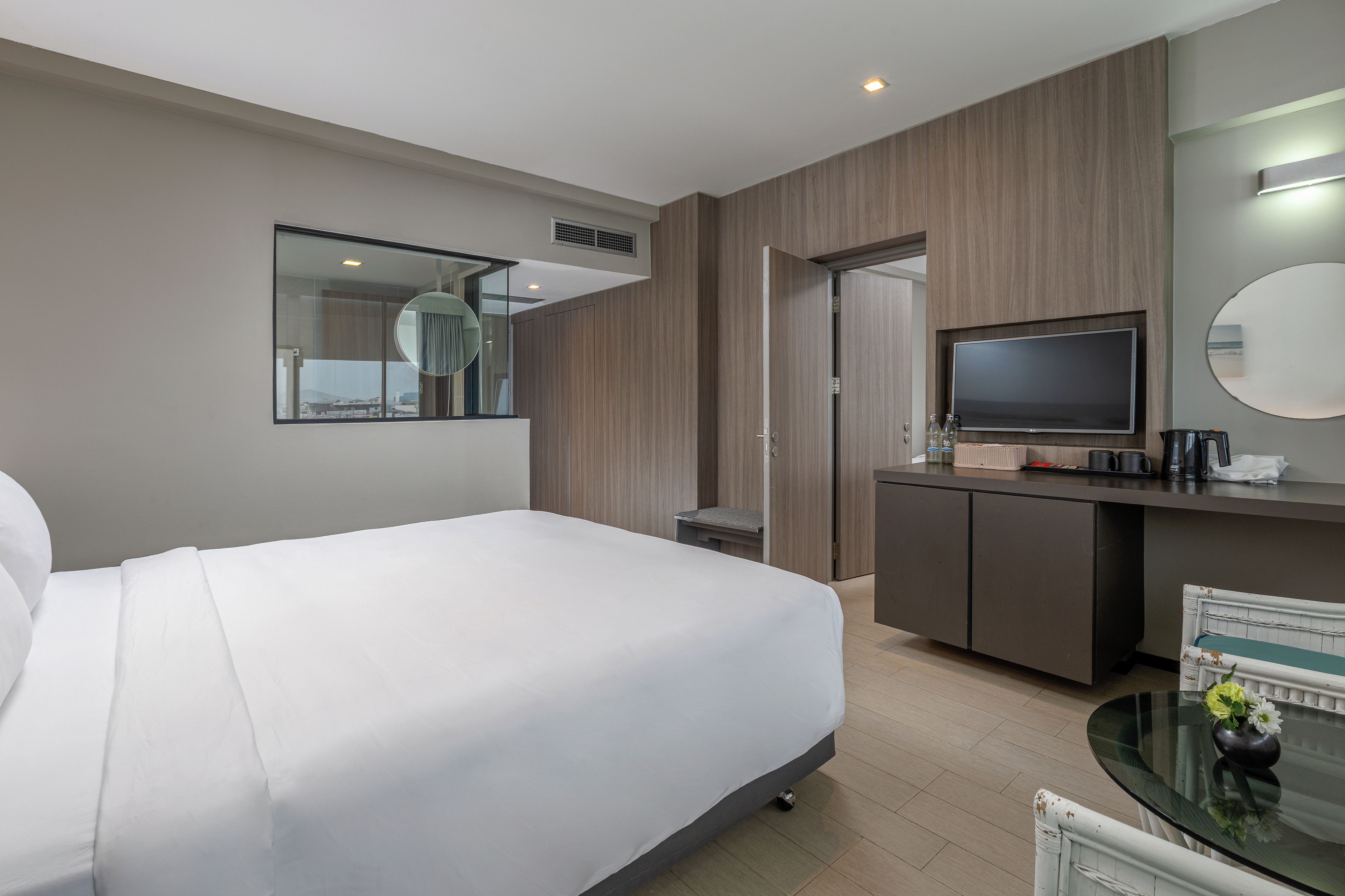 A hotel room with a bed, a desk, a television, and a mirror.