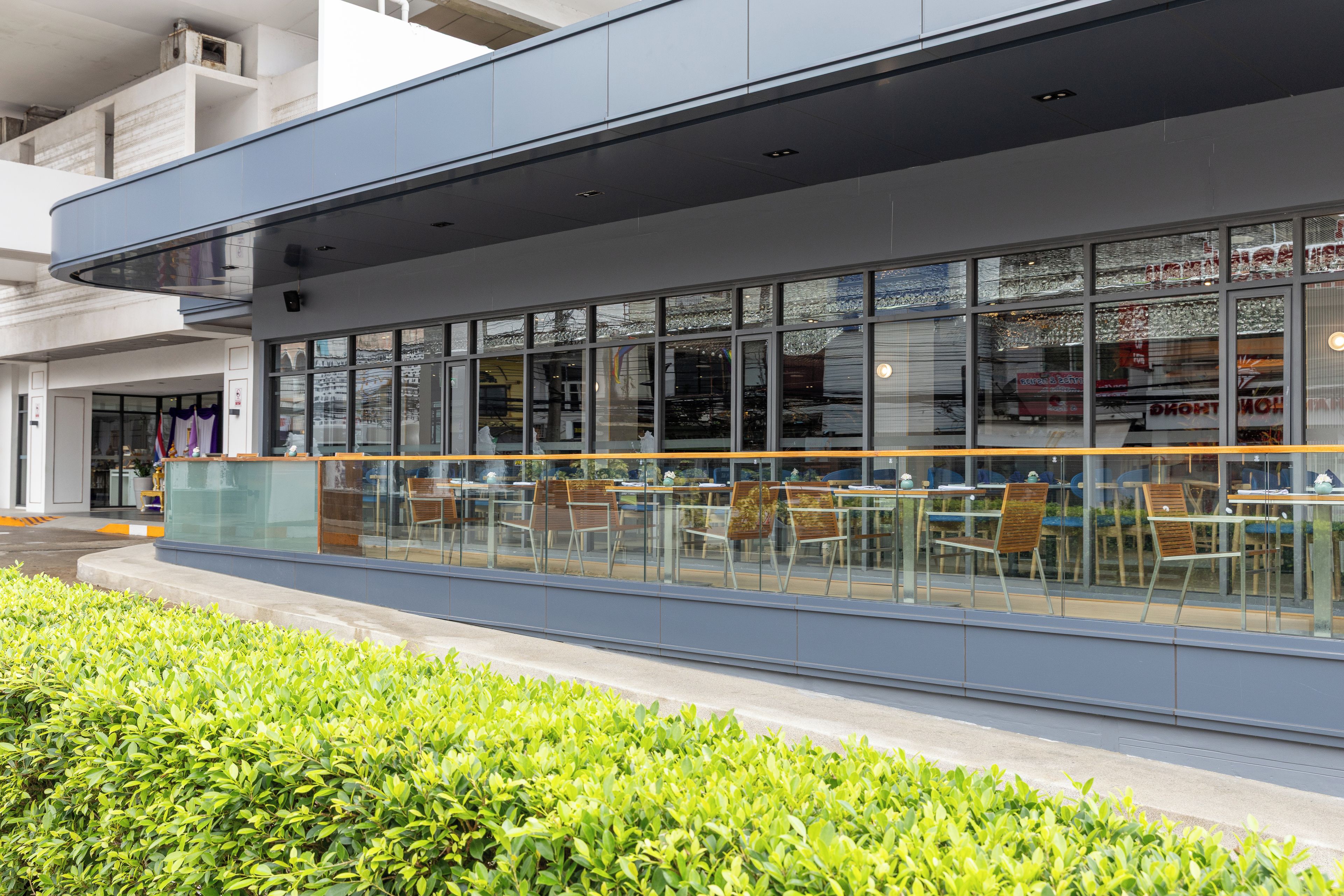 A modern building with large windows and outdoor seating.