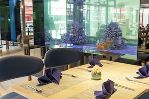 Un restaurante con una mesa dispuesta para dos, mostrando un menú, un florero con flores y servilletas dobladas.