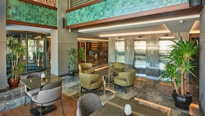 A spacious lobby with a high ceiling, a central seating area with chairs and a table, and potted plants. - Grand Hotel Gulsoy (Istanbul)