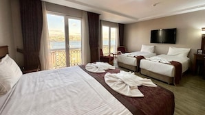 A hotel room with a large bed, two smaller beds, a TV, and a balcony with a view. - Askoc Hotel ve Spa (Istanbul)