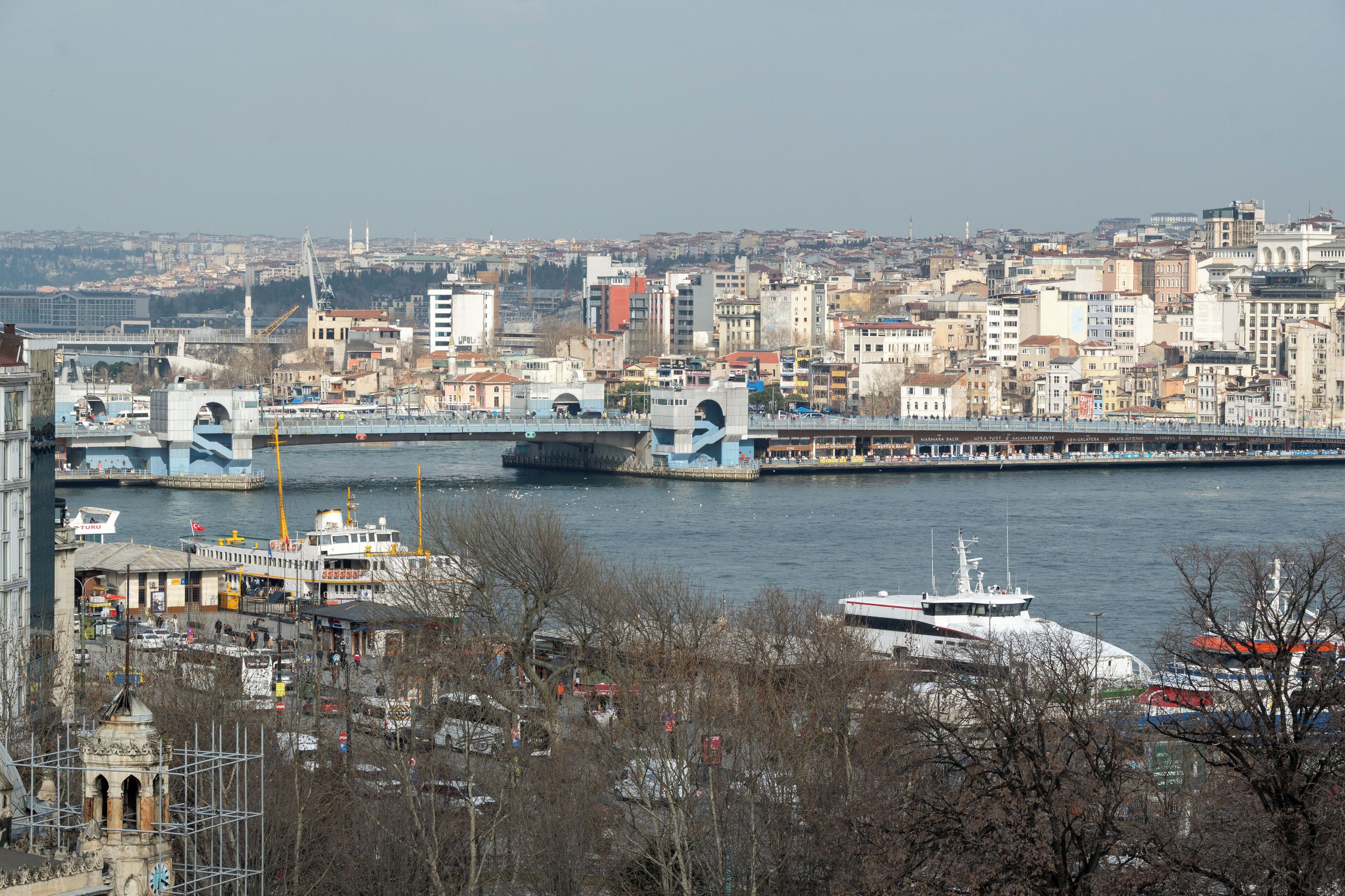 Un paisaje urbano con un puente destacado, edificios frente al agua y un muelle para barcos.