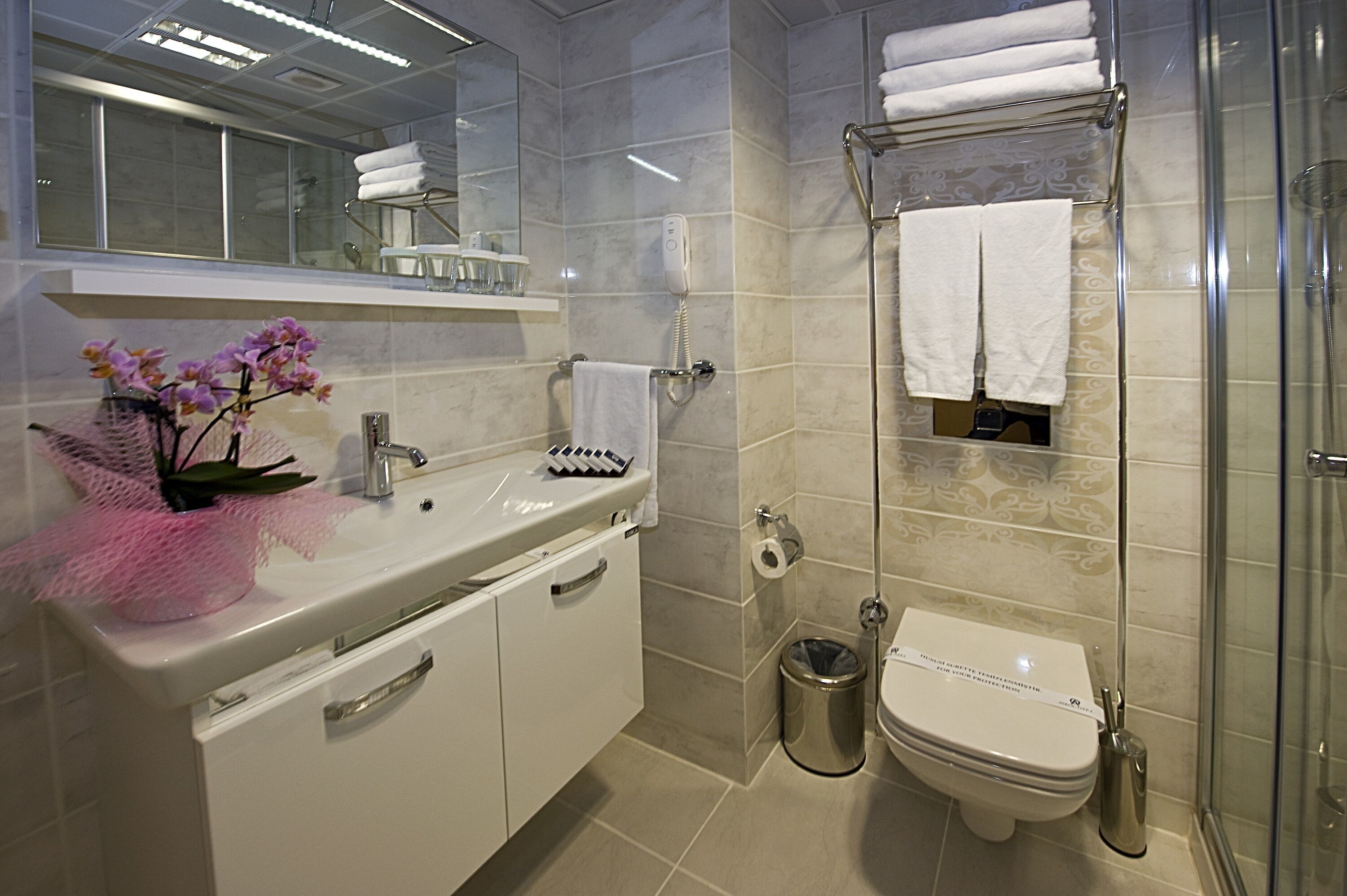 Un baño moderno con lavamanos, espejo y cabina de ducha de vidrio.