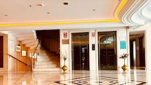 A hotel lobby with a marble floor, a staircase, and two vases with flowers. - Askoc Hotel ve Spa (Istanbul)