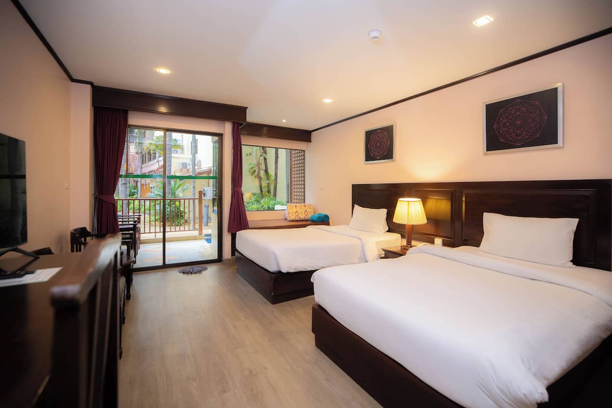 A hotel room with two beds, a TV, a desk, and a view of the outside.