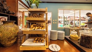 A buffet setup with multiple serving stations, including a variety of baked goods and a coffee dispenser. - Baumanburi (Patong)