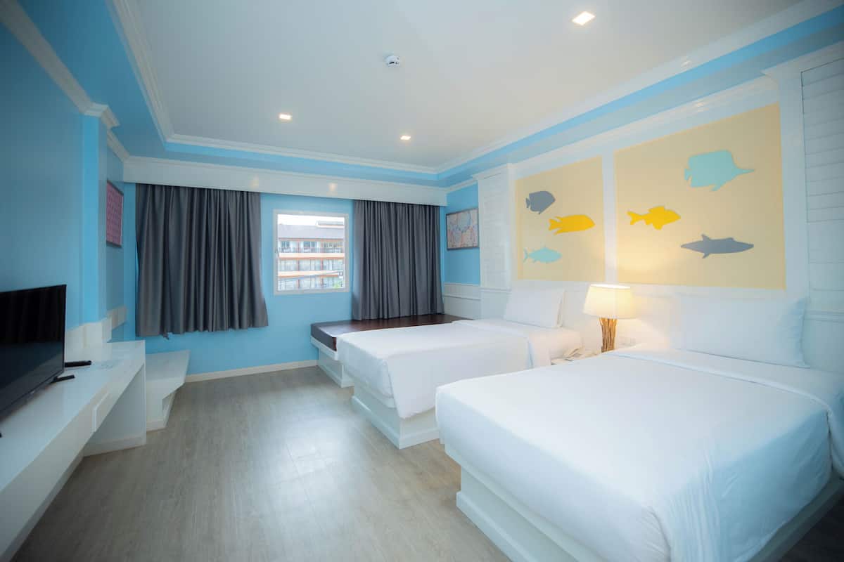 A hotel room with two beds, a TV, a desk, and a window with curtains.